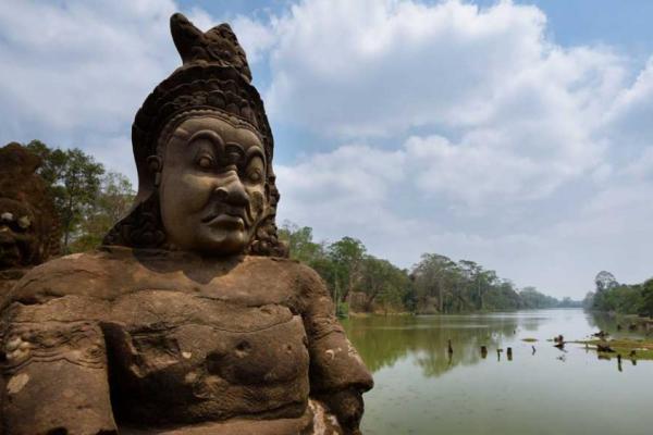 A Cambodian stone demon statue at the bank of a river