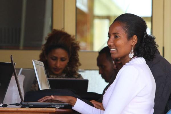 A Black woman working on a laptop in public