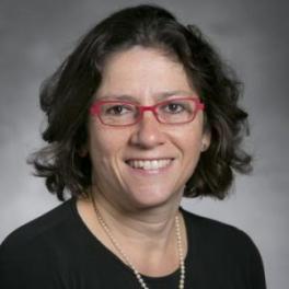 Erika Weinthal, a white woman with black, shoulder length hair, red glasses, and a pearl necklace