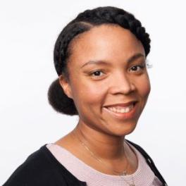 Kristi Pullen Fedinick, a Black woman with her hair braided and pulled back into a bun wearing a cardigan and pink shirt