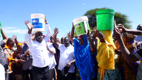 People hold buckets over their heads, waving their arms and celebrating. 