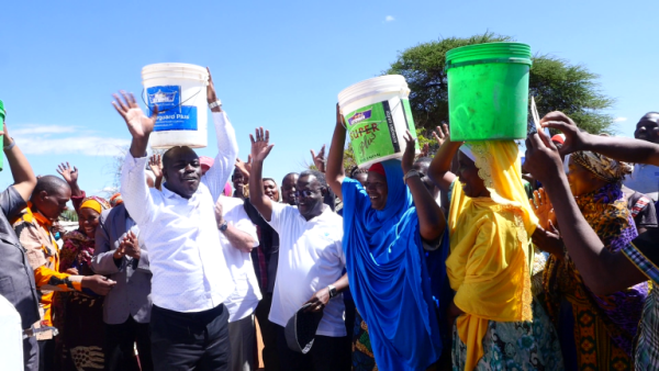 People hold buckets over their heads, waving their arms and celebrating.