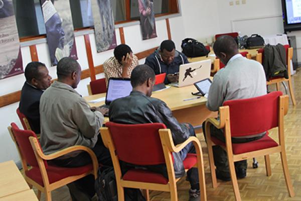 A group of Black men at a table working on computers