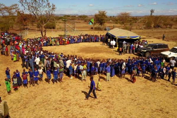 School kids in Tanzania circle up around a tent for a ceremony. 