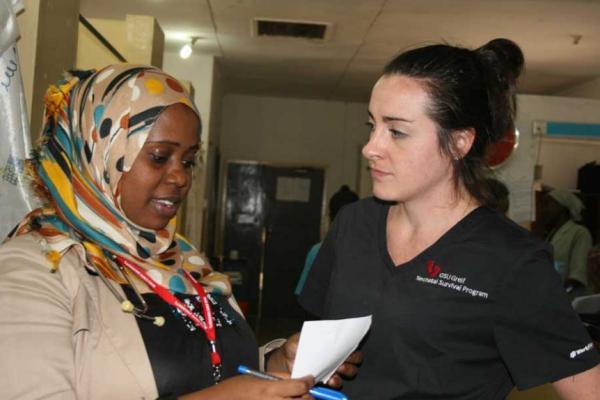 Two nurses, a Black women wearing a headscarf and a white women with brown hair tied into a bun