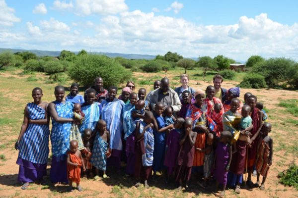 A mixed race, mixed age group of people, mostly Black. They are wearing colorful patterns and smiling