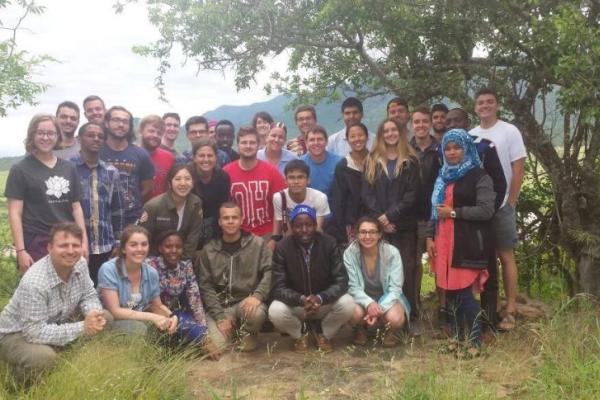 A mixed race group of people posed together beneath a tree