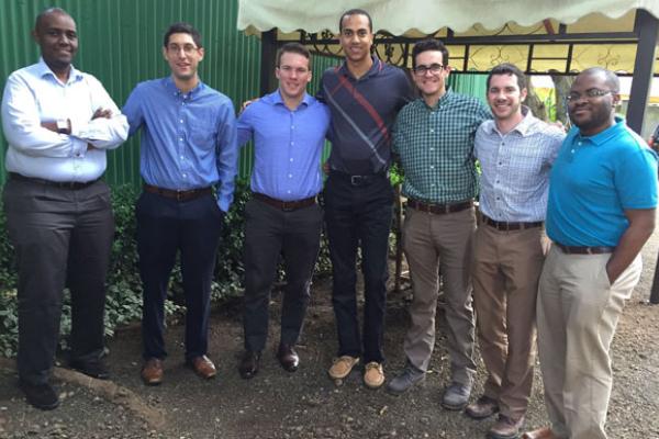 A mixed race group of men standing with their arms around each other's shoulders