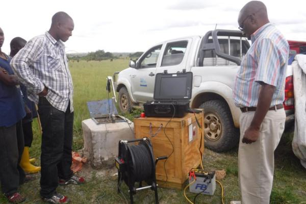 A group of Black men standing around field equipment and a truck