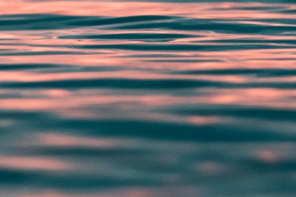 orangish hue on surface of calm water with few waves