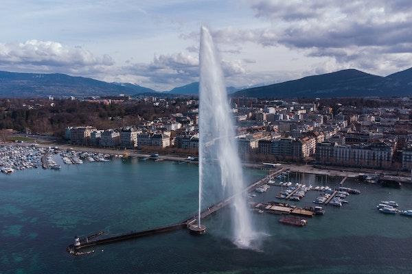 water fountain with a back drop of the city under blue skies in the city of Geneva