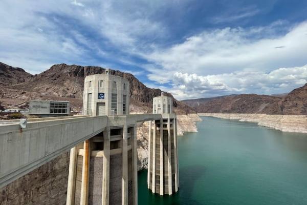 Lake that has receded as seen with water marks on the cliffs and a bridge looking structure that protrudes into the water.