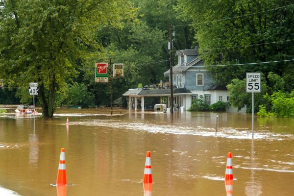Flooded street with street and store signs and cones under water. A building flooded too.