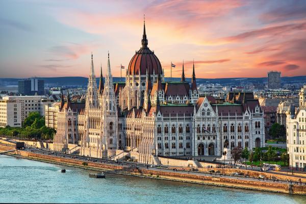 A cityscape and the waterfront Parliament Building in Budapest under blue-pink skies.