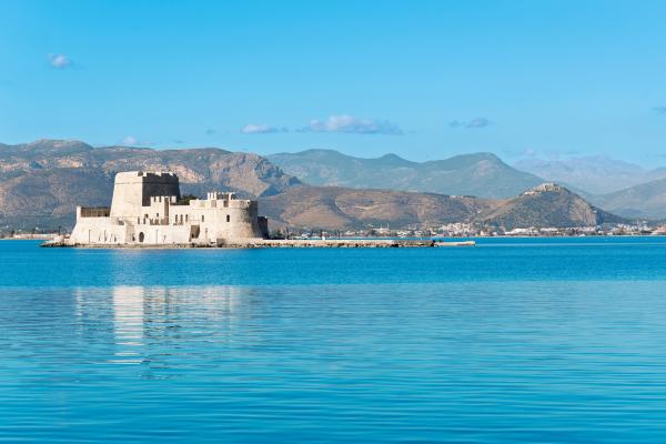 View from the water of a castle and hill in the background.
