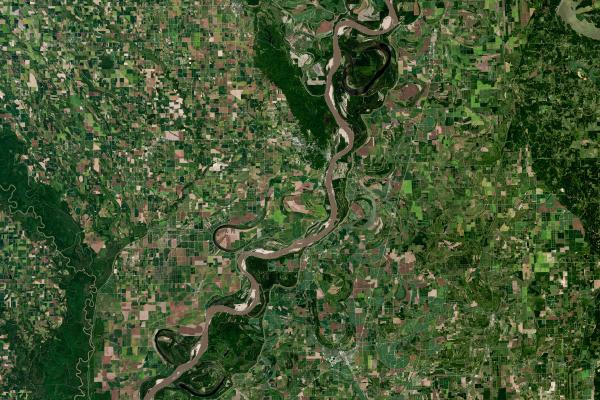 Aerial view of a river and green farmland around.