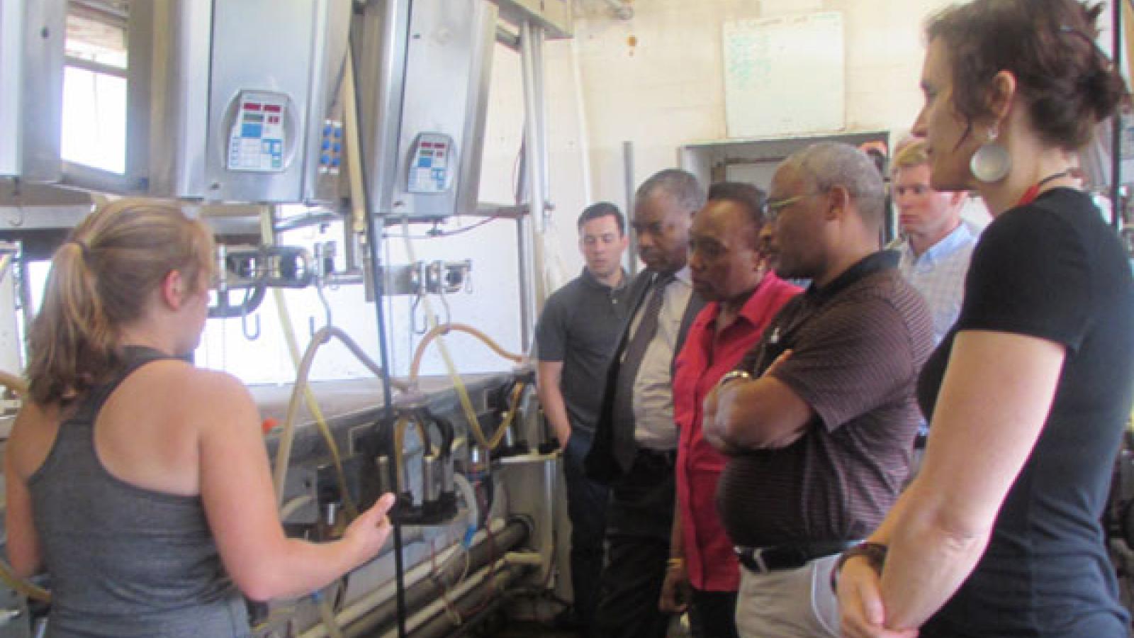  mixed race, mixed gender group of people in a mechanized facility. Some are in business wear, others are in tee shirts